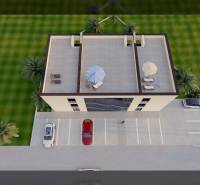 A view from above of a building with a parking lot, rooftop terrace, and surroundings with greenery.