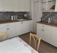 A kitchen with white cabinets, patterned tiles, and a floor with a wood decor in a 2-room apartment.