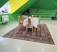 Interior of a family house with a dining table, colorful walls, and a patterned carpet.