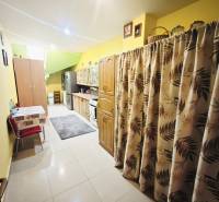 A kitchen in a family house with wooden decor, yellow walls, and patterned curtains.