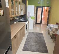 A kitchen in a family house with tiles, wooden cabinets, and a dining table.