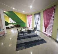 A bright living room with colorful walls, a seating area, and pull-out beds in a family house.