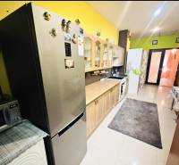 A kitchen in a family house with a stainless steel refrigerator and wooden decor cabinets.