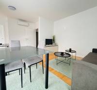 Living room with a sofa, folding table, and wood-patterned floor in a holiday apartment.