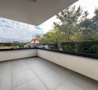 The terrace of a recreational apartment in Novalja with glass railings and a view of the surrounding houses.