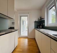 The kitchen of a holiday apartment with a wood-decor floor and a terrace.