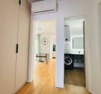 Hallway of a holiday apartment with a view of the bathroom and living room, floor with wooden decor.