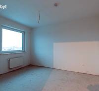An empty room without flooring in a 2-room apartment with a large window and a radiator.