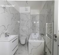 A bathroom with white tiles, a bathtub, and a sink in a 2-room apartment.