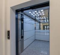 Interior of an elevator with stainless steel panels and a mirror, visible buttons.