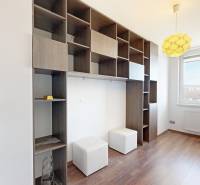 A room in a 3-room apartment with a shelving system, wooden decor flooring, and light.