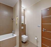 Bathroom with a bathtub and toilet in a 3-room apartment, with a wooden decor floor.