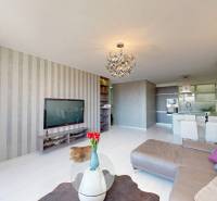 Living room with wood-patterned flooring, a comfortable sofa, and a spacious kitchen in a three-room apartment.