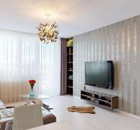 Living room in a 3-room apartment with a striped wall, sofa, and TV on the wall.