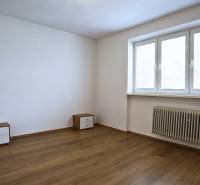 A room in a 3-room apartment with a wooden decor floor and simple furniture.