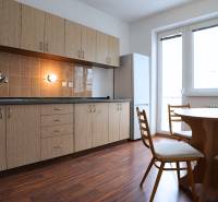 A kitchen in a 3-room apartment with a wooden decor floor and a dining table.