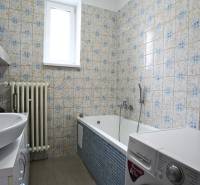 A bathroom with a bathtub and a washing machine in a 3-room apartment with retro tiles.