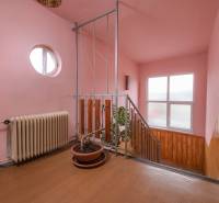 A staircase in a family house with a wooden decor, pink walls, and potted plants.