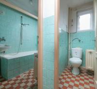 A bathroom in a family house with a bathtub and green tiles.