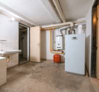 Basement space with a boiler in a family house, showing a sink and pipes.