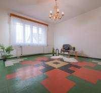 Interior of a family house with an ornamental floor, an armchair, a table, and a plant.