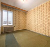 A room in a family house with patterned wallpaper and carpeted floor.