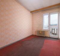 A room in a family house with a window, wallpaper, and a radiator, carpeted floor.