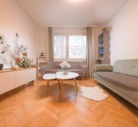 Living room in a 3-room apartment with a wooden decor floor, sofas, and plants.