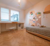 Children's room in a 3-room apartment with a bed, table, and floor with a wooden decor.