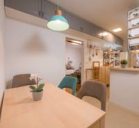 Dining table with chairs, light, shelves, and decorations in a 3-room apartment.