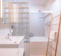 A bathroom with a bathtub, a sink, and a wooden ladder in a 3-room apartment.