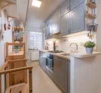 A kitchen in a 3-room apartment with a functional counter, wooden shelves, and light cabinets.