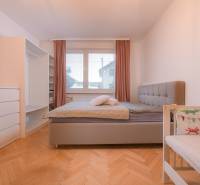 Bright bedroom with a built-in wardrobe and a crib in a 3-room apartment, floor with wood decor.