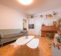 Living room of a three-room apartment with a wooden decor floor and a piano.