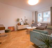 A bright living room with a piano, wooden decor flooring, and comfortable sofas.