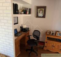 Home office with a desk, books, and photos on shelves in a family house.