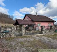 A family house in Lukovištia with a pink facade, a stone fence, and a gate.