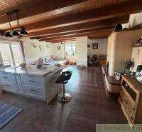 Interior of a family house with ceiling beams, kitchen, living room, and floor with wooden decor.