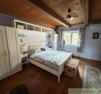 A bedroom in a family house with a wooden decor floor and a floral pattern on the wall.