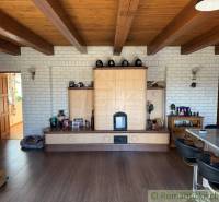 Interior of a family house with a tiled stove, decorative wooden beams, and a floor with a wooden design.