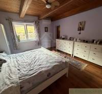 Bedroom in a family house with wooden beams and a floor with a wooden decor, furnished with a bed.