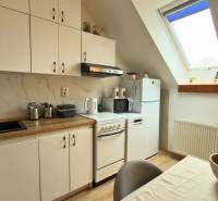 A kitchen in a 2-room apartment with white cabinets and a skylight.