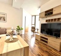 Living room in a three-room apartment with a wooden decor floor and simple furnishings.