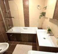 A bathroom in a 3-room apartment with a bathtub, sink, and decorative tiles.
