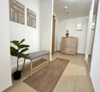 Interior of a 3-room apartment with light furniture, a bench, and decorative paintings.