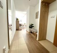 Entrance hall in a 3-room apartment with tiles and a bench, leading to the living room.