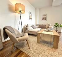 Living room in a 3-room apartment with a wooden decor floor, comfortable seating, and a lamp.