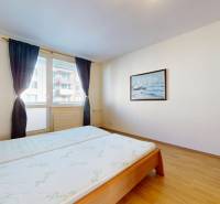 Bedroom with wood-patterned flooring in a 3-room apartment, large window with dark curtains.