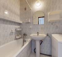 Bathroom with a bathtub in a 3-room apartment, tiles with a subtle pattern, washing machine.
