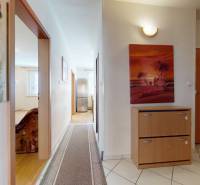 The hallway of a 3-room apartment with a light floor and colorful paintings on the walls.